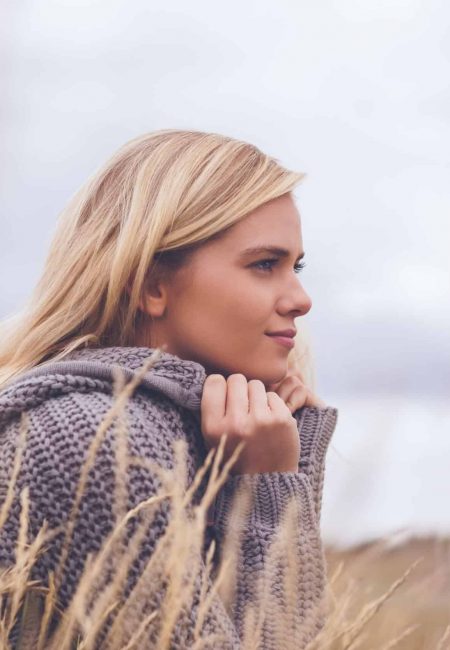 Close up side view of a cute thoughtful young woman lying on grass at beach