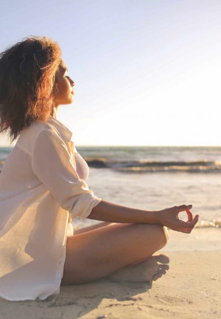 Girl doing yoga at the beach, at sunset time