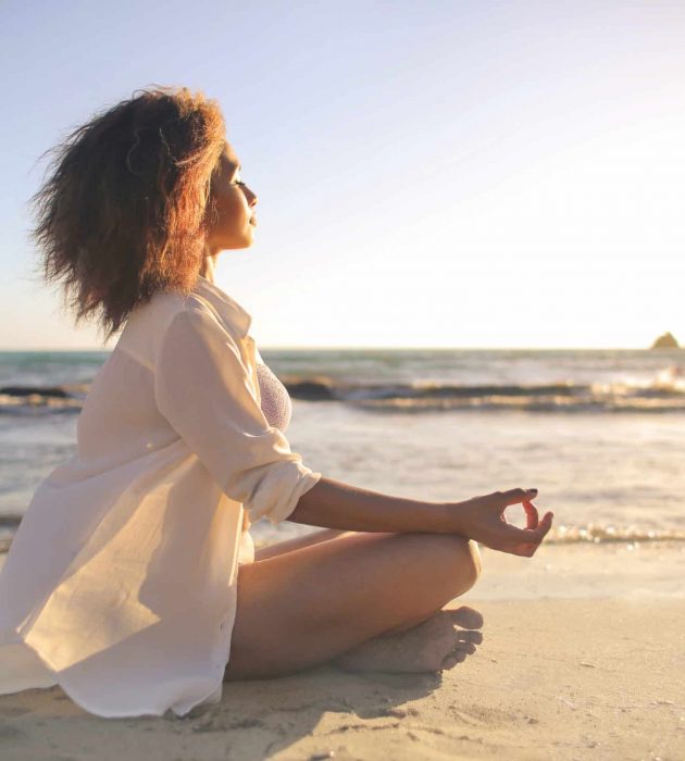 Girl doing yoga at the beach, at sunset time